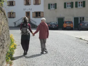 Paar spaziert Hand in Hand durch gepflasterte Straße.