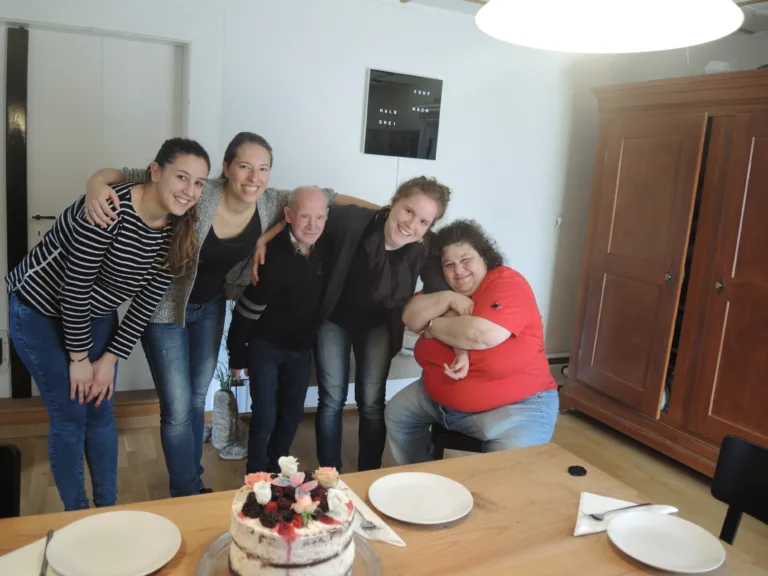 Gruppe lächelt am Tisch mit Kuchen.