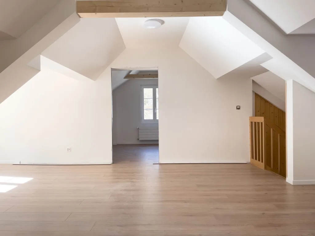 Leerer Dachboden mit Holzboden und Dachschrägen.