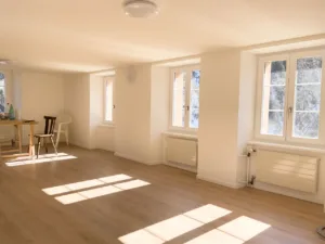 Helles Zimmer mit Holzboden und großen Fenstern