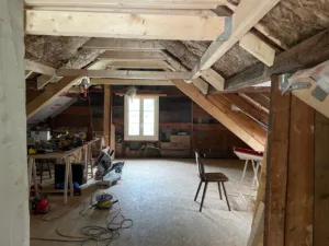 Dachboden-Renovierung mit Holzbalken und Werkzeugen im Raum.