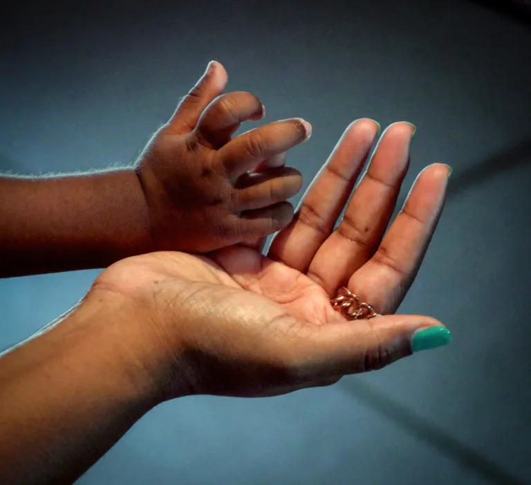 Erwachsene Hand hält Kinderhand, symbolisiert Fürsorge