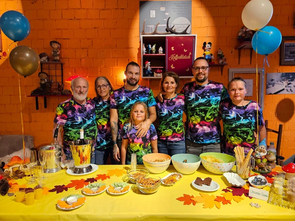 Familienfeier mit bunten Shirts und gedecktem Tisch.