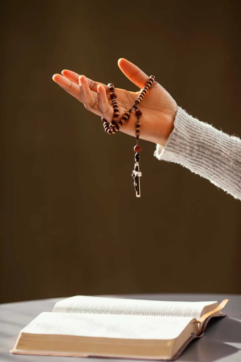 Hand hält Rosenkranz über Bibel
