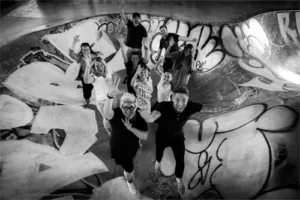 Gruppe springt fröhlich im Graffiti-geschmückten Skatepark.